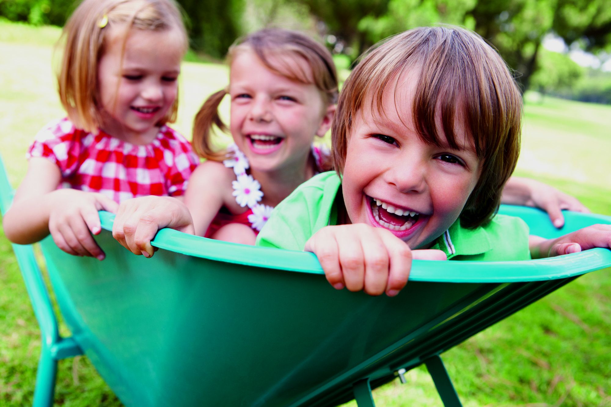 Lachende Kinder in einer Schubkarre im Garten